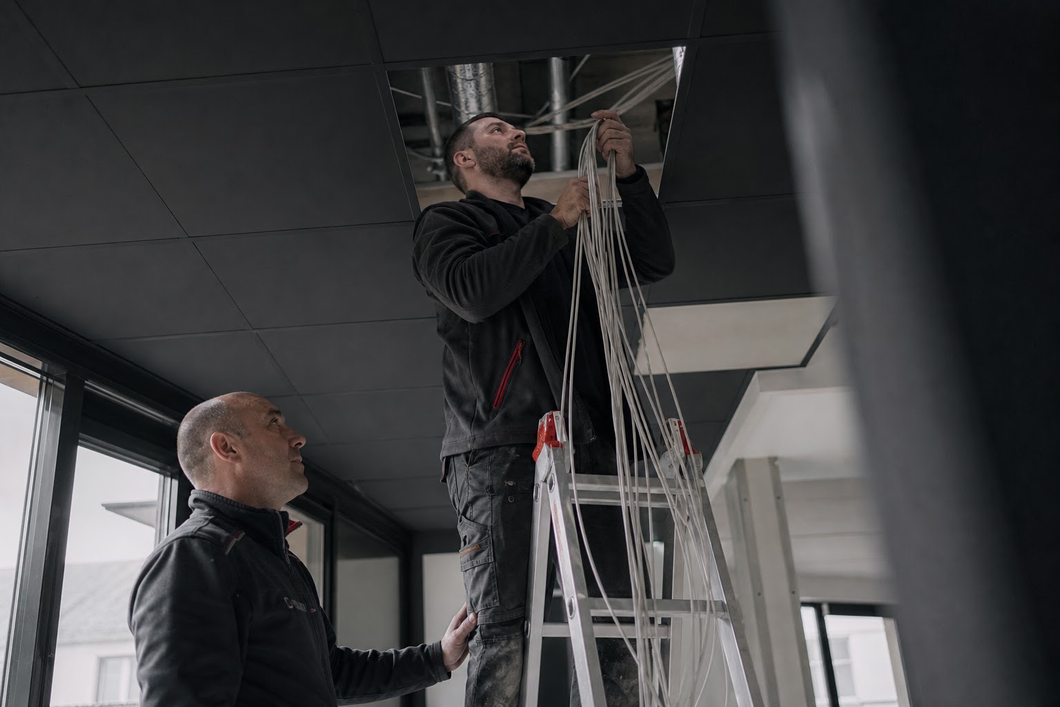 Technik ťahá štruktúrovanú kabeláž v podhľade
